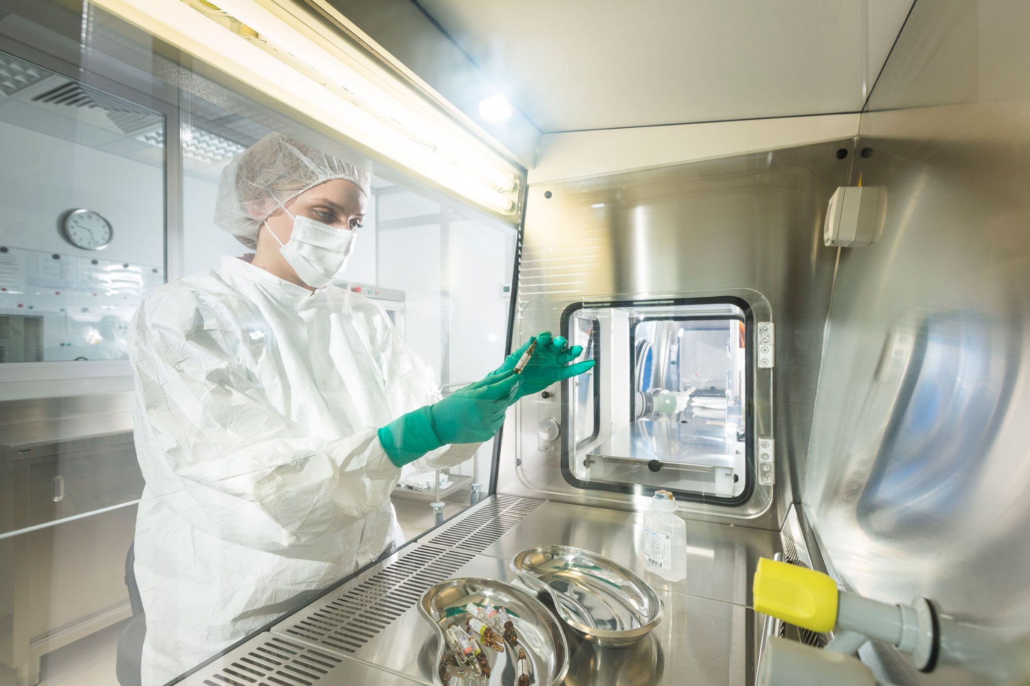 Mitarbeiterin in steriler Schutzkleidung am Isolator